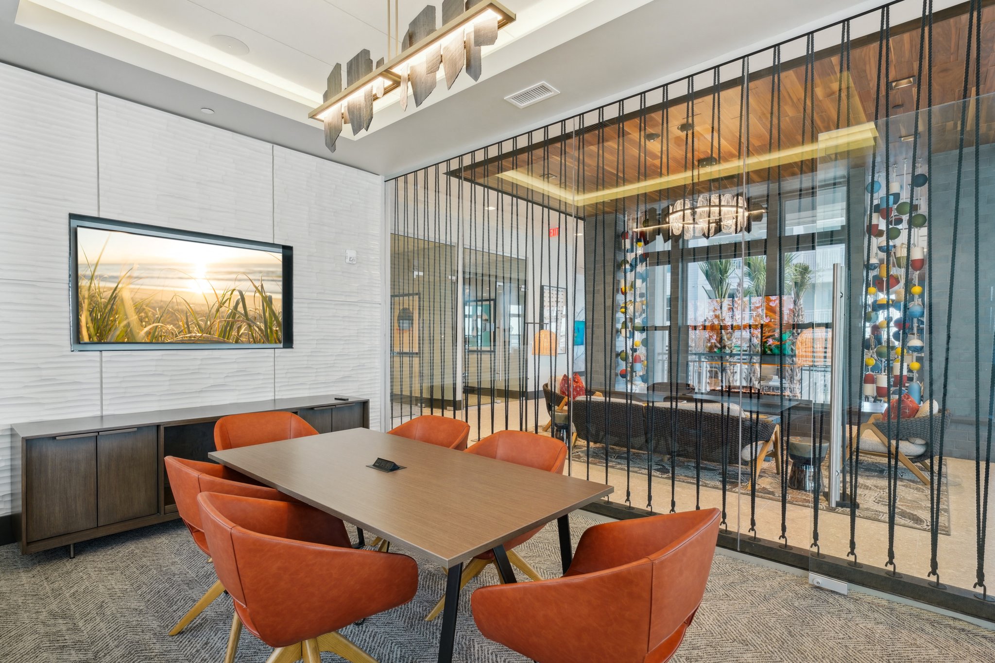 A conference room with a long table and orange chairs.