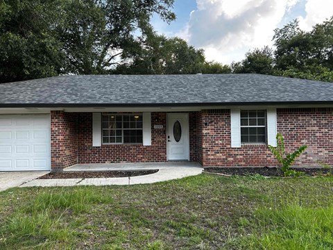 A small brick house with a white door and windows.