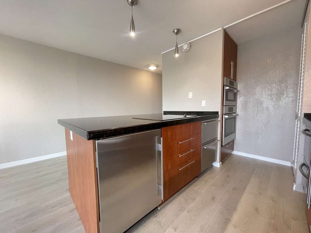 A kitchen with a stainless steel refrigerator and wooden cabinets.