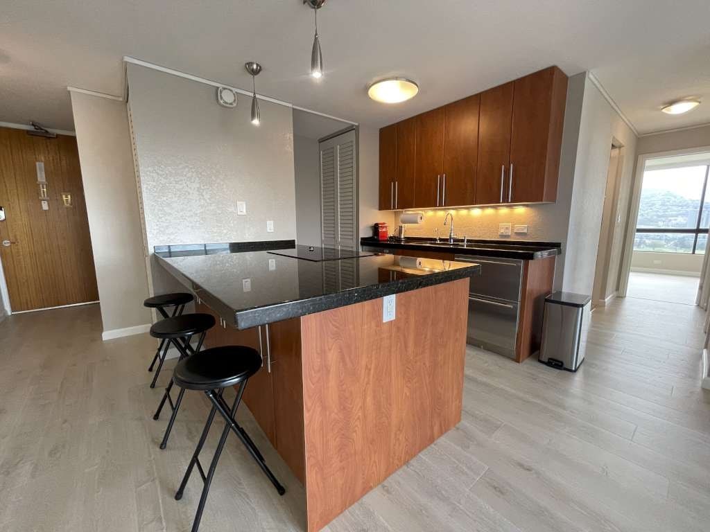 A kitchen with a wooden island and black countertop.