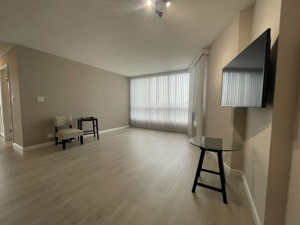 A living room with a glass table and a television on the wall.