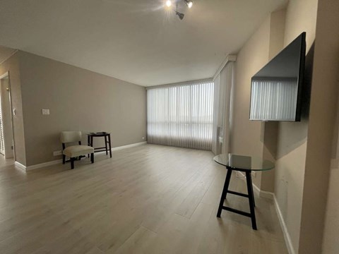 A living room with a glass table and a television on the wall.