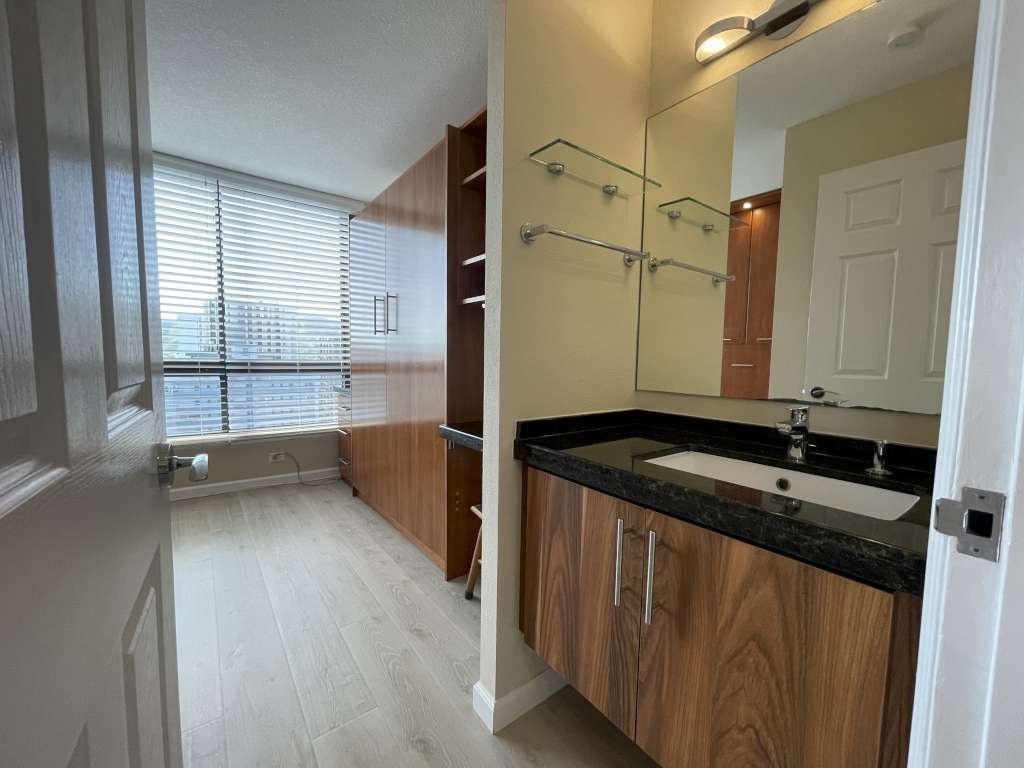 A bathroom with a sink, mirror, and shower.