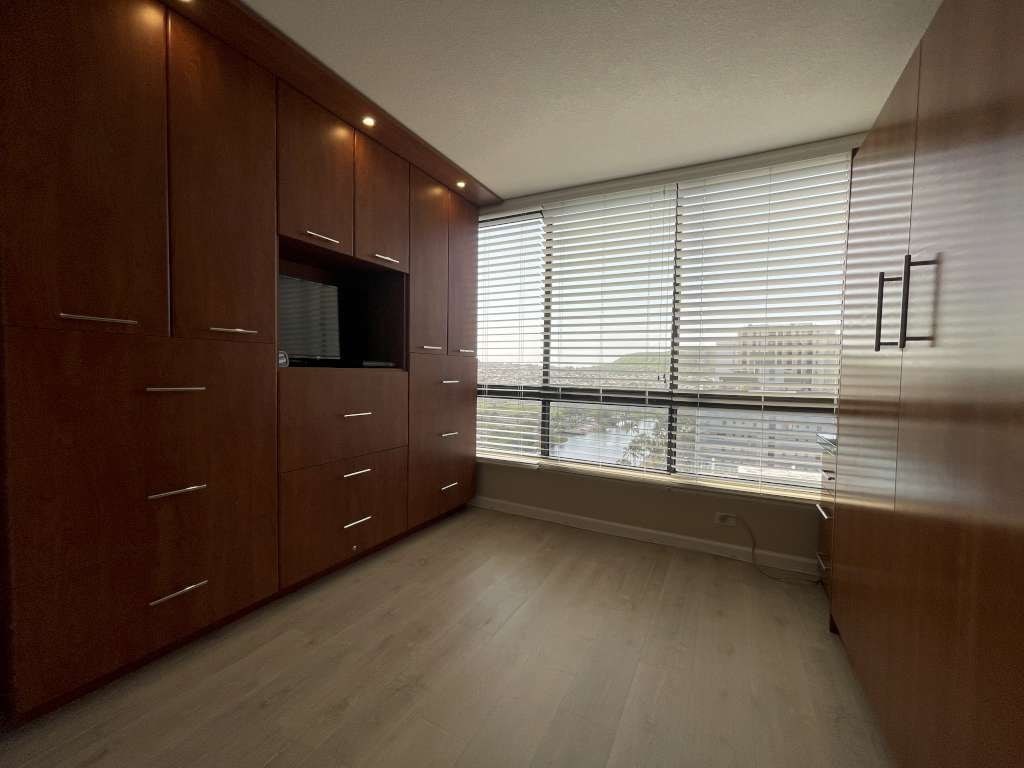 A room with wooden cabinets and a window with blinds.