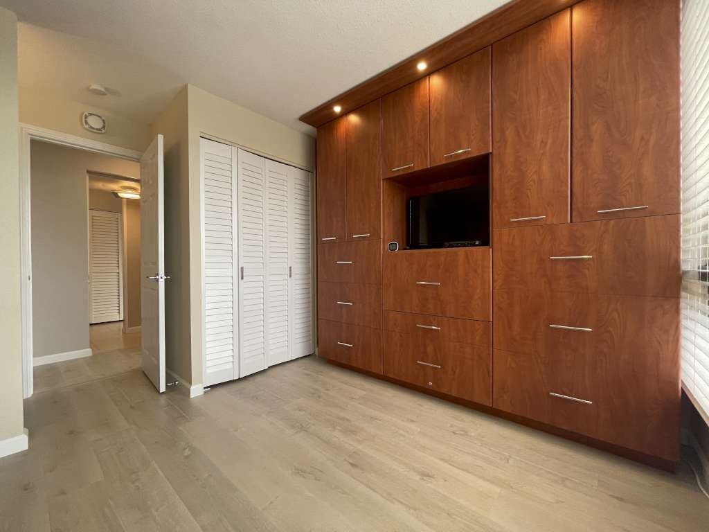 A room with wooden cabinets and a television built into the wall.