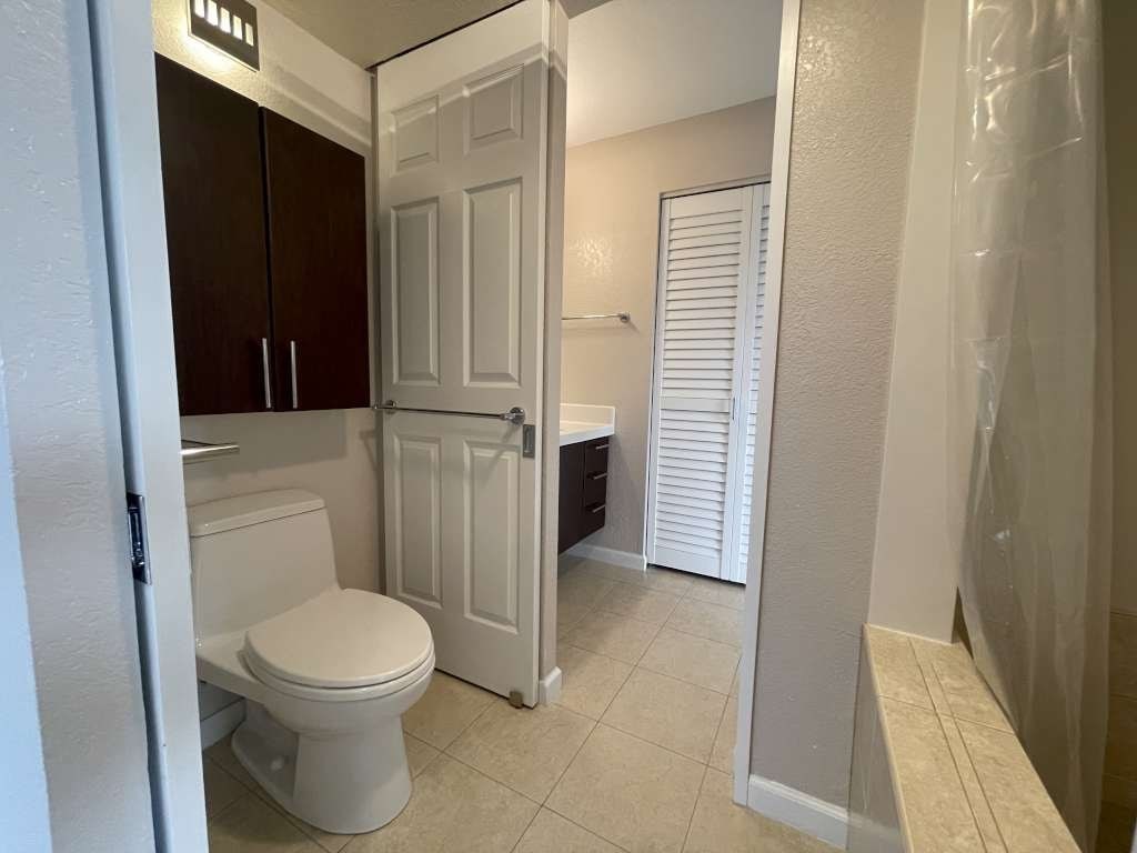 A white toilet sits in a bathroom with a white door and brown cabinets.