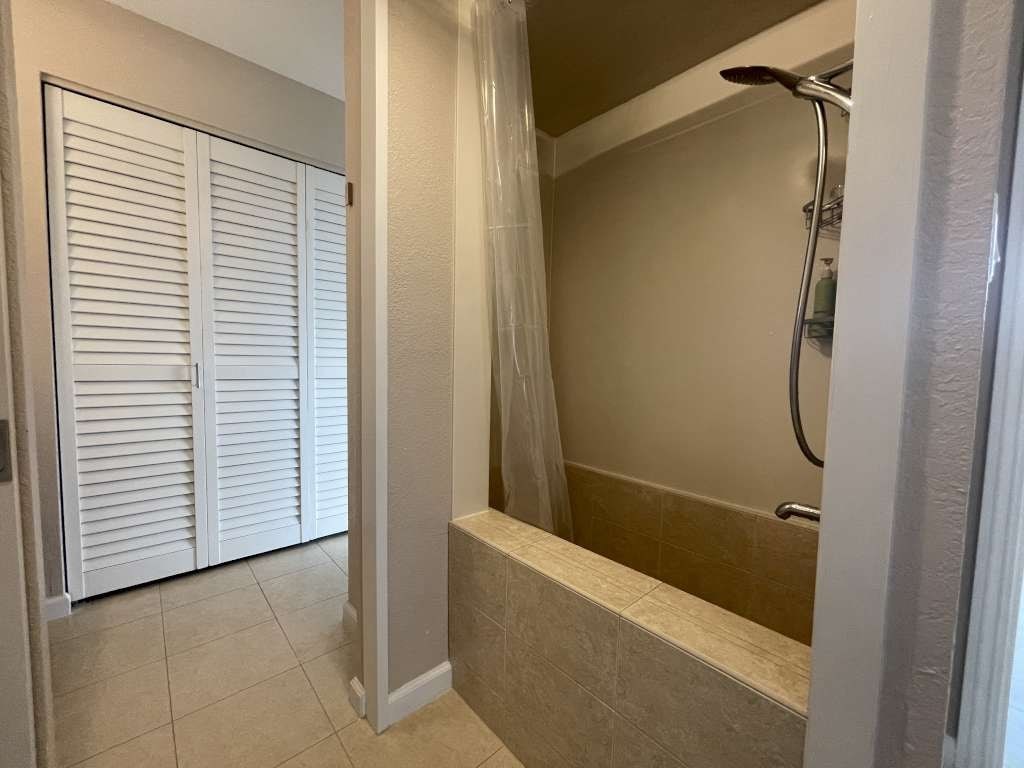 A bathroom with a shower and a white door.