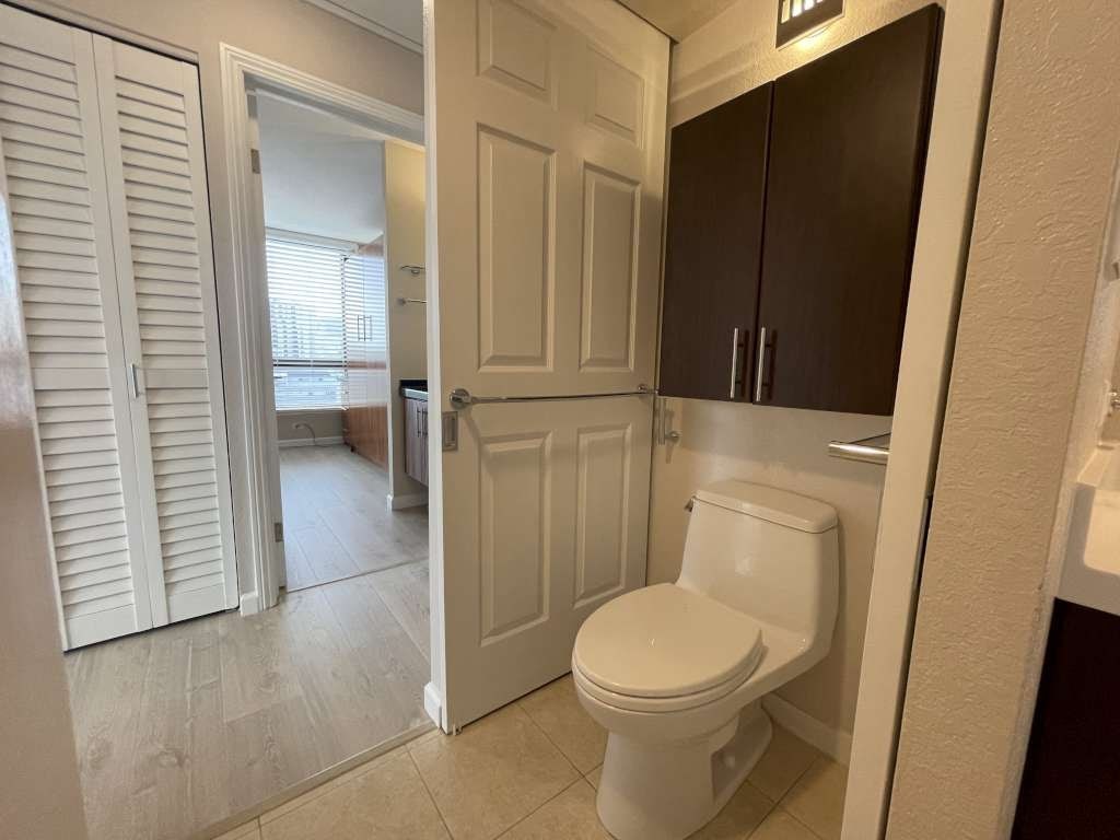 A white toilet in a small bathroom with a white door and a brown cabinet.