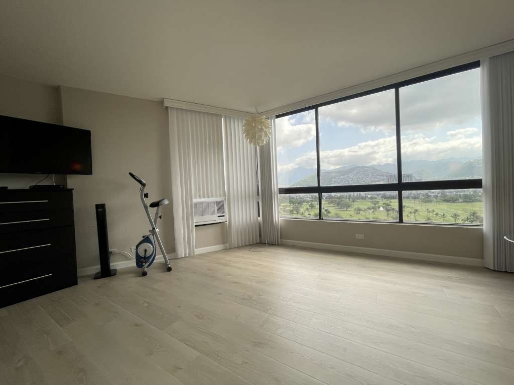 A room with a large window overlooking a green landscape.