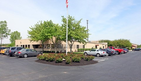 a parking lot full of cars in front of a building with a flag