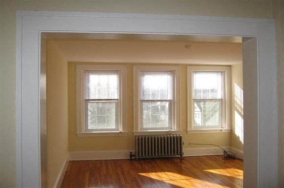 an empty room with a radiator and four windows