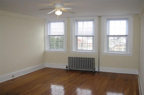 an empty living room with a ceiling fan and three windows