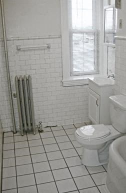 a white bathroom with a toilet and a window