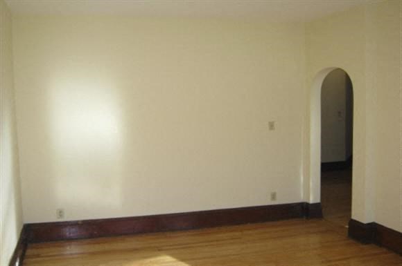 an empty room with a white wall and a wooden floor