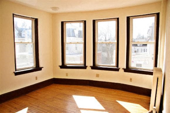 a living room with five windows and a wooden floor