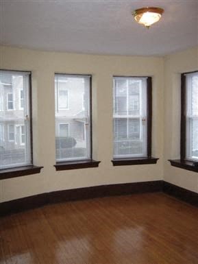 a living room with three windows and a hard wood floor