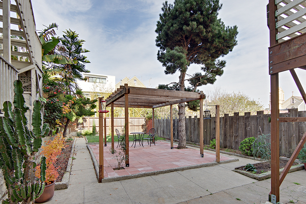a backyard patio with a pergola and a table and chairs