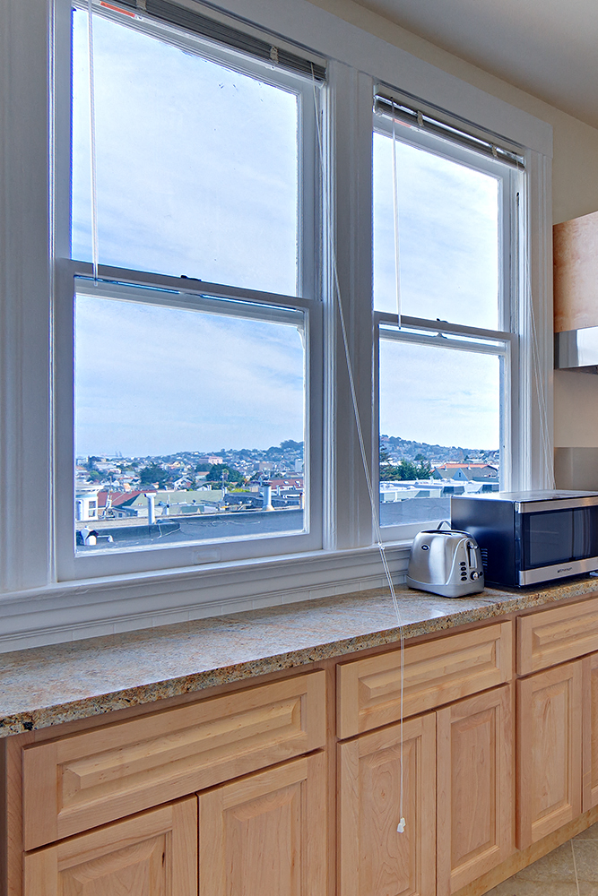 a kitchen counter with a toaster and three windows