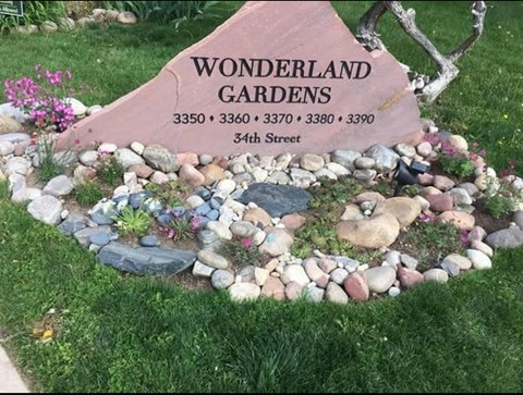A garden sign that says "Wonderland Gardens" is in front of a garden.