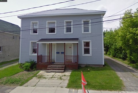 a blue house with a front porch and a sidewalk