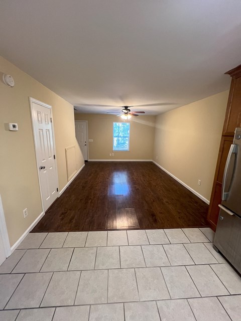 an empty living room with wooden floors and a ceiling fan