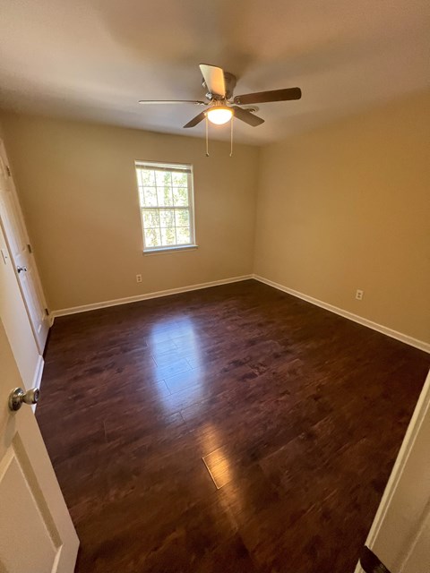 a empty room with a ceiling fan and wood floors