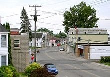 A street with a blue car and a white garage.