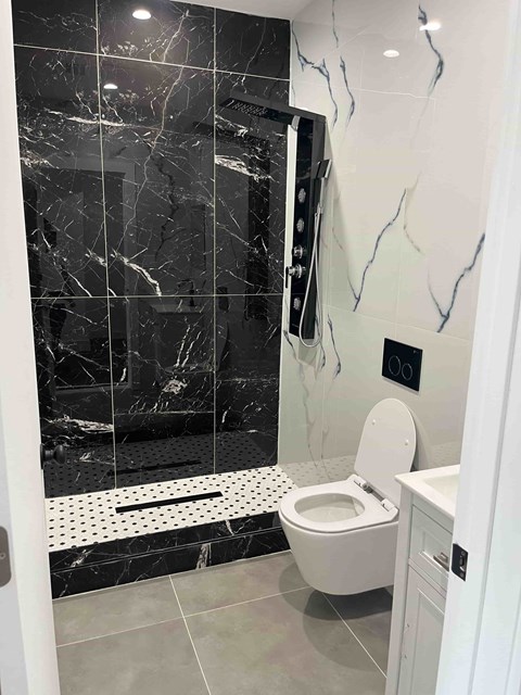 a black and white bathroom with a toilet and shower