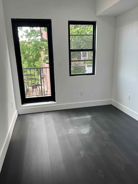 an empty room with a window and wooden floors