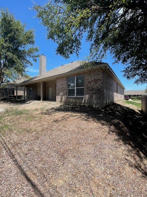 a brick house with a gravel yard and trees