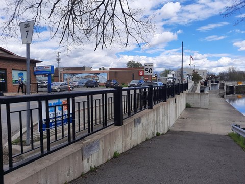 A sidewalk runs alongside a body of water with a sign that reads 50.