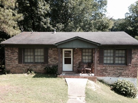 A small house with a white door and a brick wall.