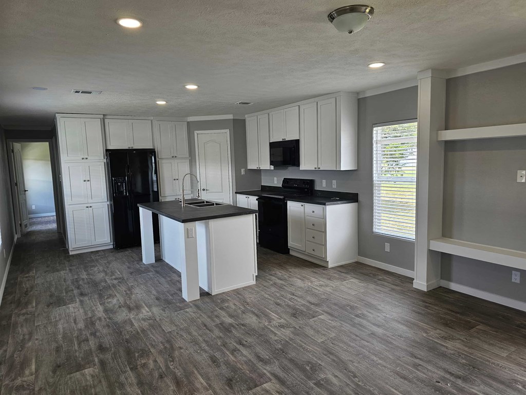 A kitchen with white cabinets and a black fridge.