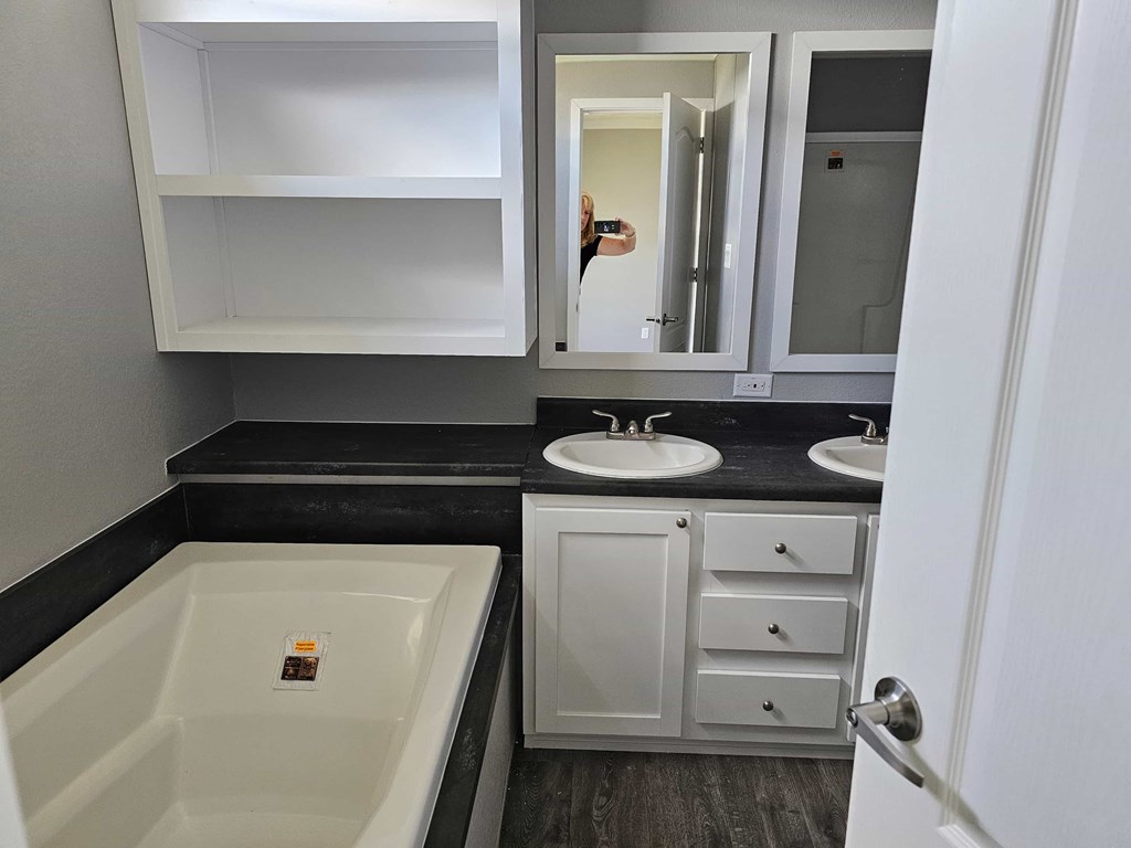 A white bathroom with a black counter top and a white tub.