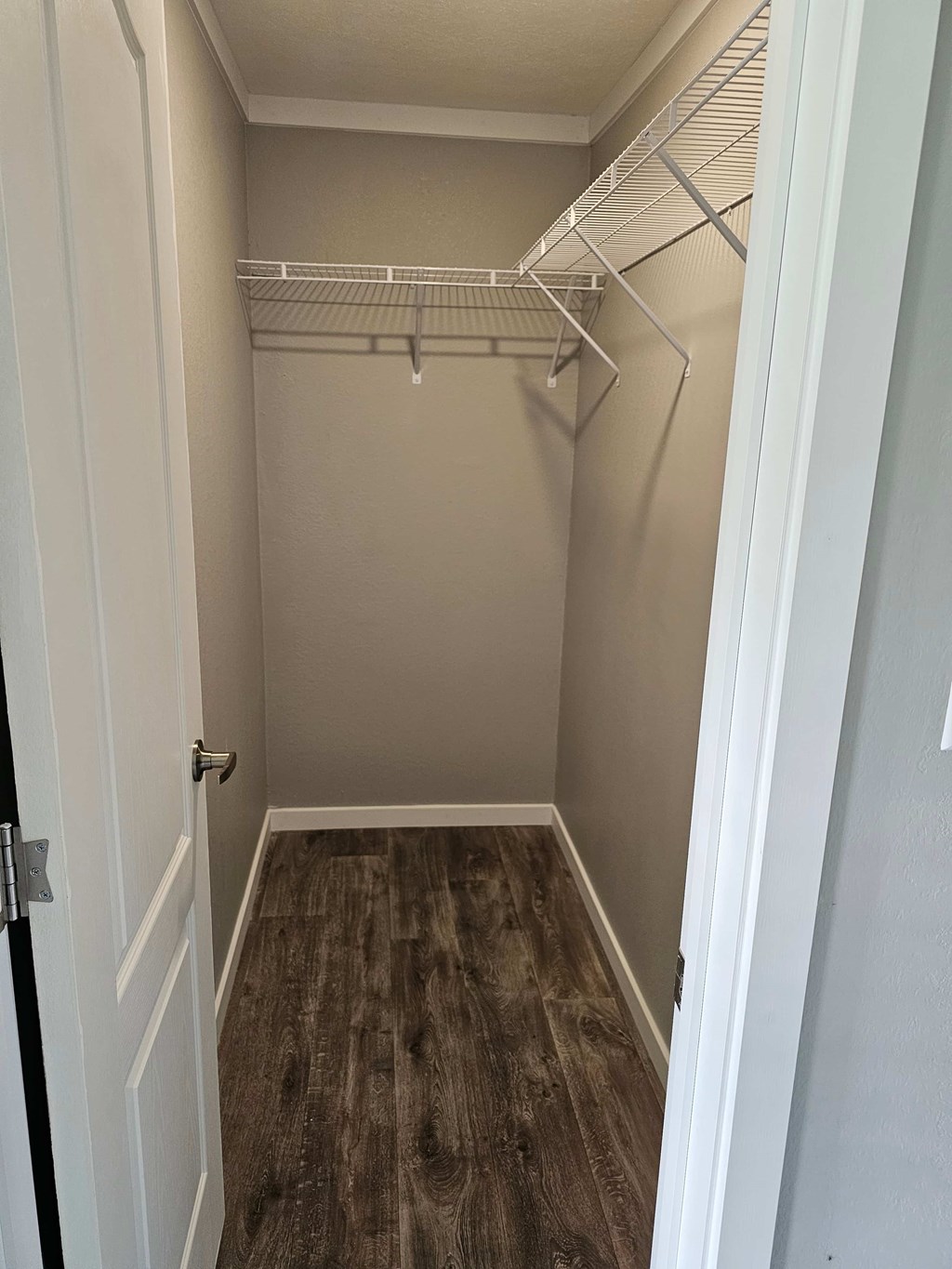 A walk in closet with a white door and shelves.