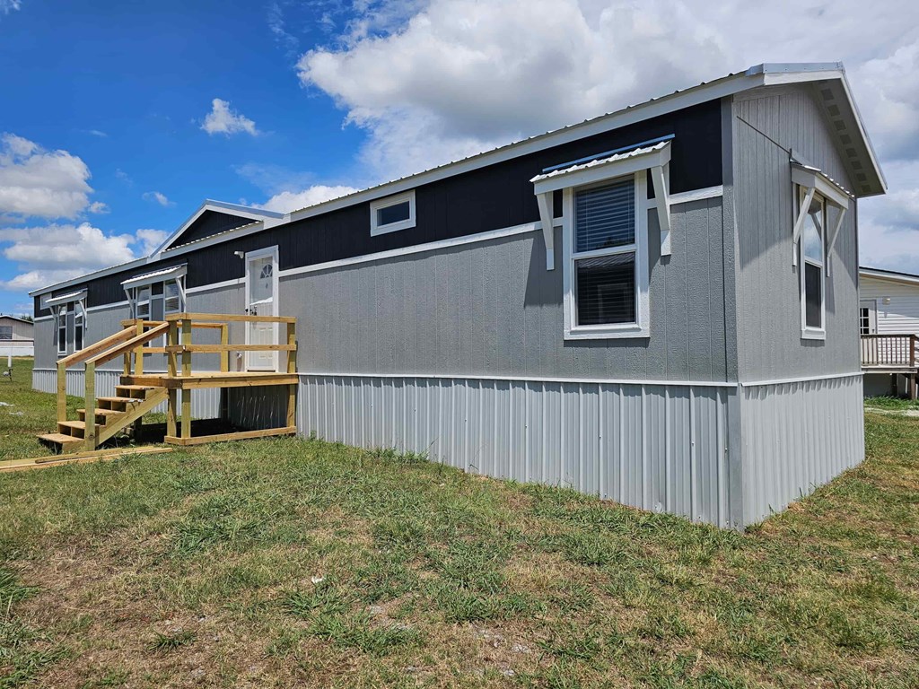 A grey house with a wooden staircase leading to the door.