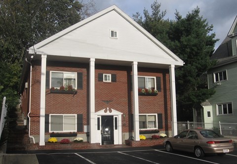 A white church with a car parked in front.