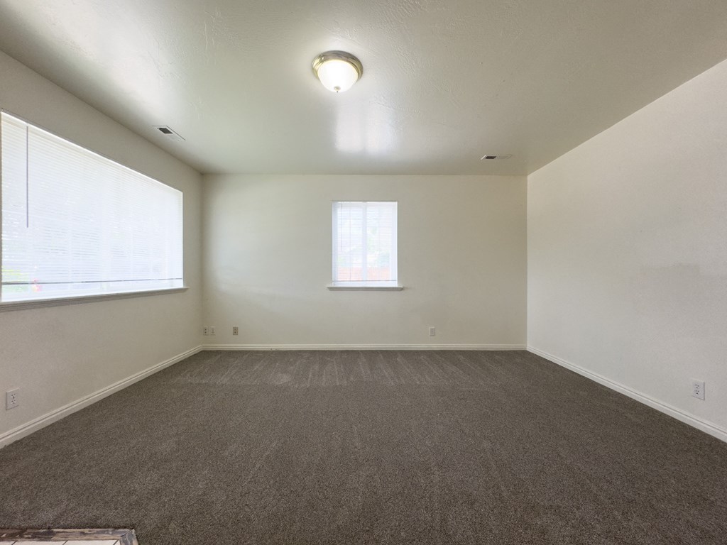 A room with a carpeted floor and a window.
