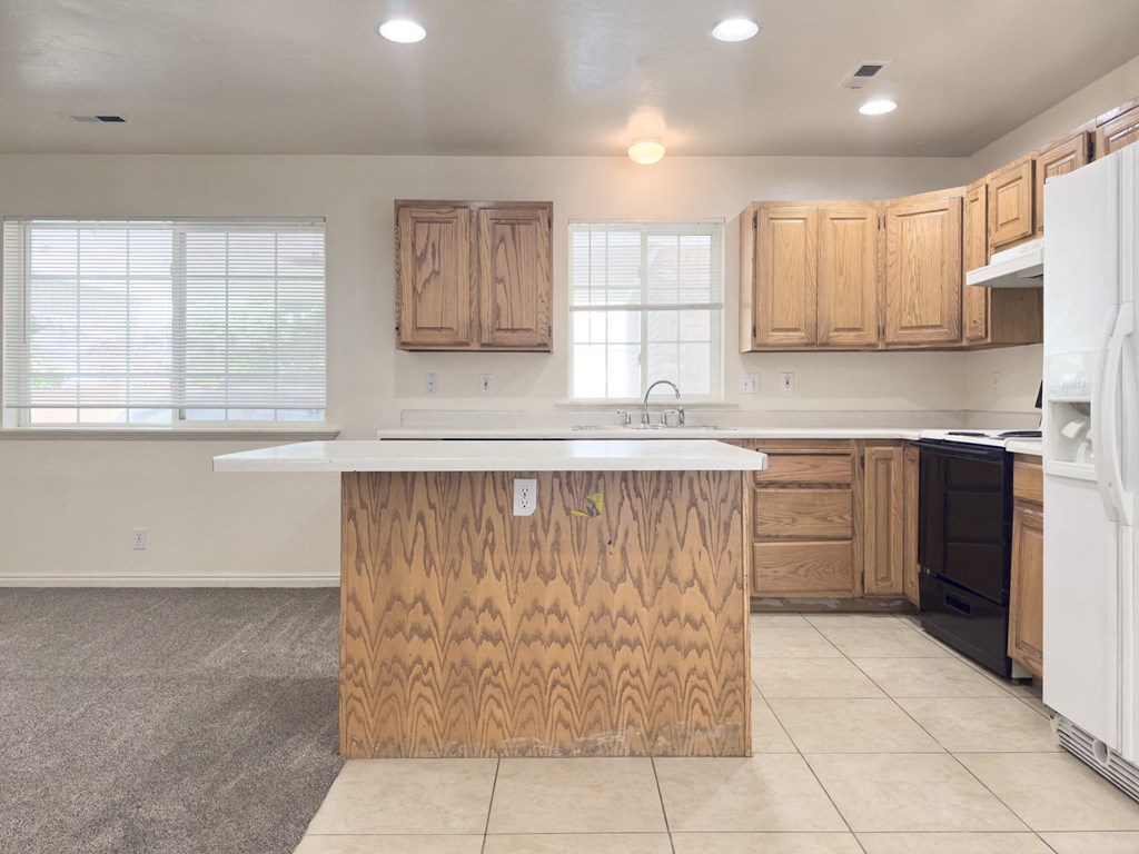 A kitchen with a white fridge and wooden island.