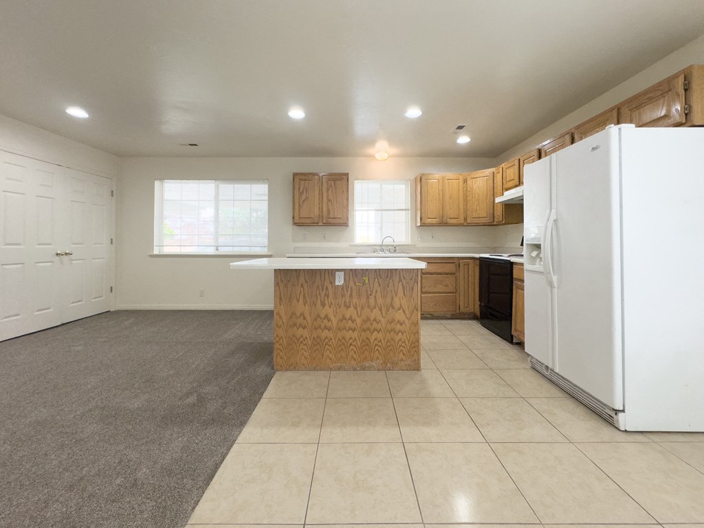 A kitchen with white appliances and wooden cabinets.