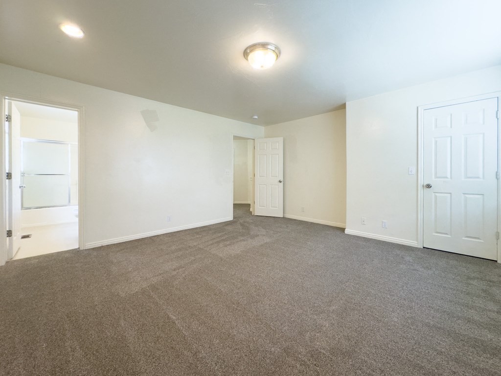 A spacious room with carpeted floor and white walls.
