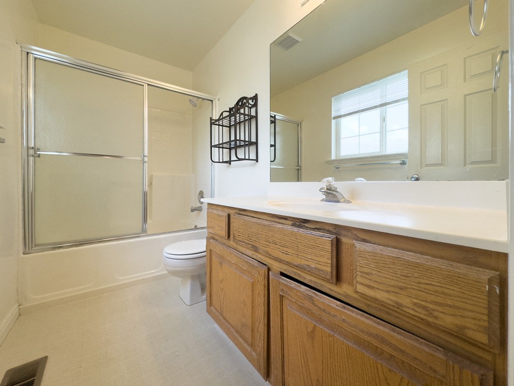 A bathroom with a toilet, sink, and mirror.