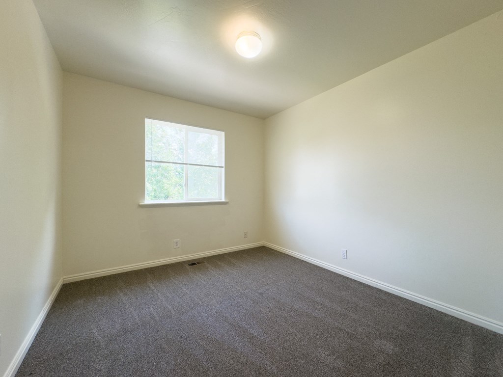 A room with a window and carpeted floor.