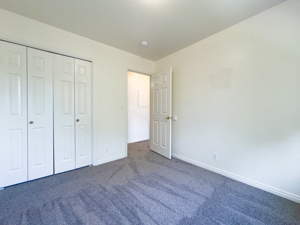 A room with white walls and a grey carpet.