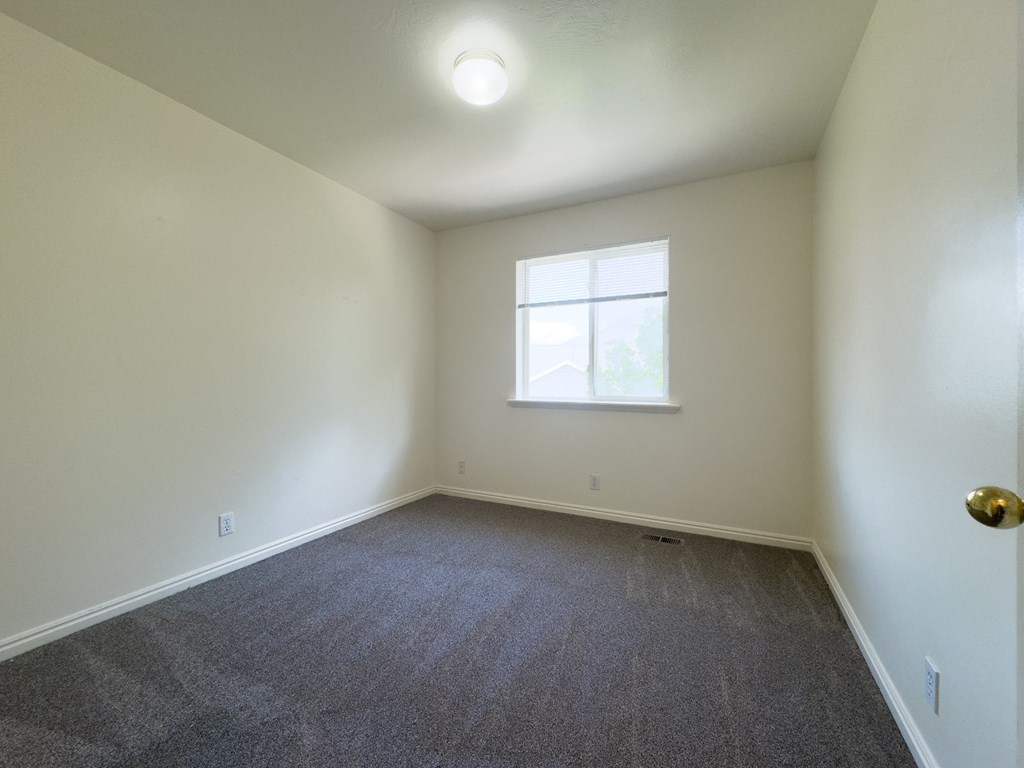 A room with a carpeted floor and a window.