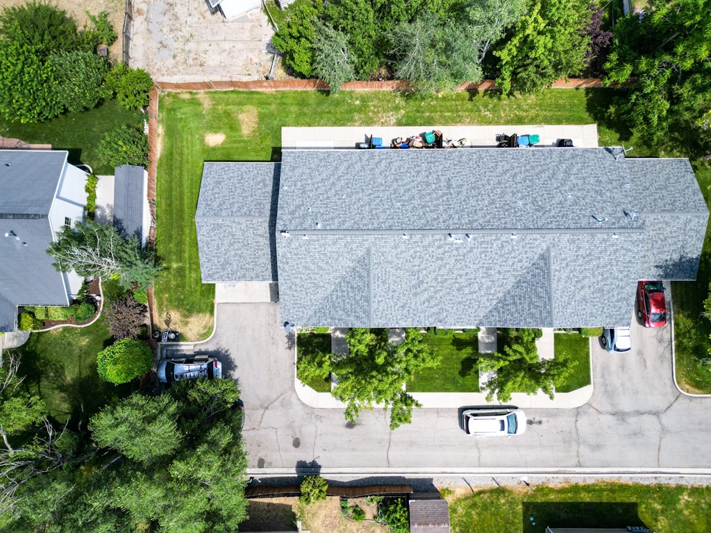 A large building with a grey roof is surrounded by a grassy area and trees.