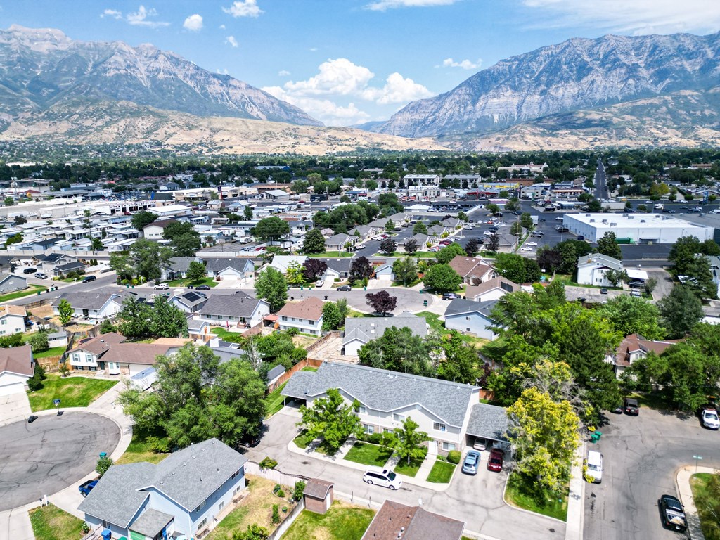 A residential area with houses and cars in the foreground and mountains in the background.