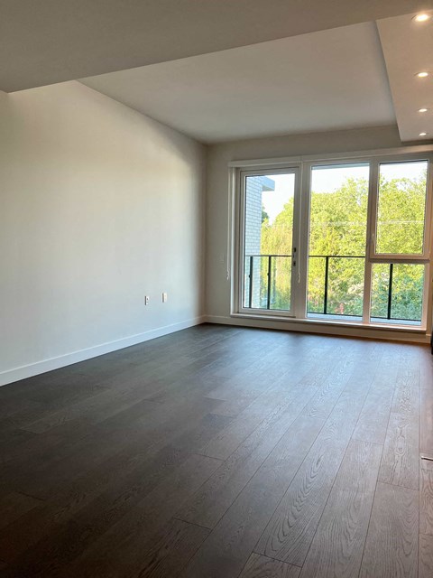 an empty living room with wood flooring and large windows