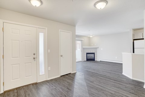 an empty living room with a white door and a fireplace