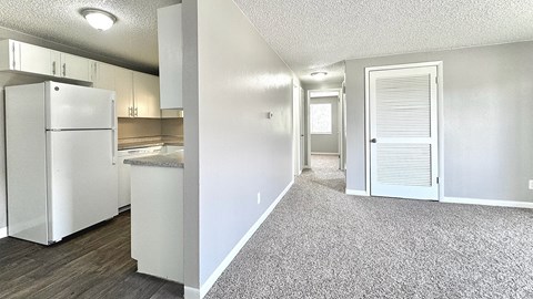 A kitchen with a white refrigerator and a white door leading to another room.
